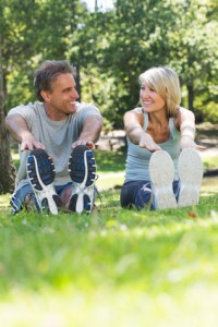 Happy couple looking at each other while stretching in the park